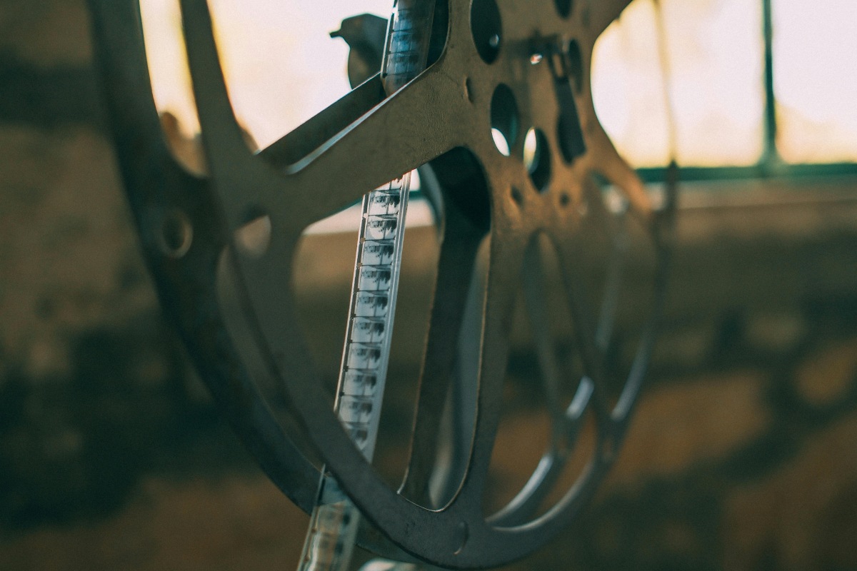 Close-up of an old film reel with filmstrip threaded through it in warm light.